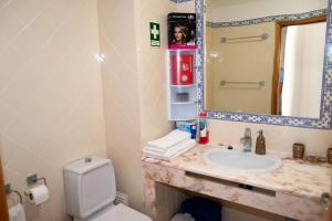 a bathroom with a sink and a toilet and a mirror at Clube Meia Praia in Lagos