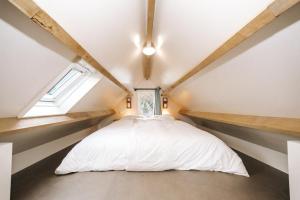une chambre avec un lit blanc dans un grenier dans l'établissement Thalassa Beach Houses, à Zandvoort