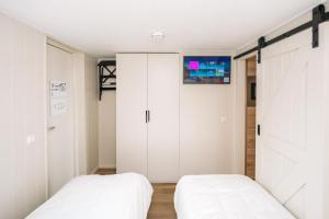 2 Betten in einem Schlafzimmer mit weißen Schränken in der Unterkunft Thalassa Beach Houses in Zandvoort