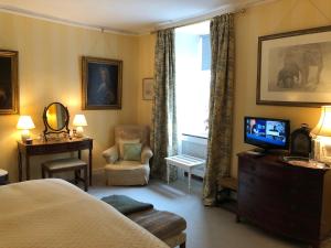 1 dormitorio con 1 cama, TV y silla en Marston Hall, en Grantham