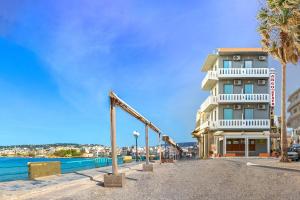 ein Hotel am Strand mit Palmen und einem Gebäude in der Unterkunft Kumba At Koum Kapi in Chania