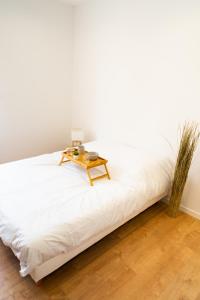 een wit bed met een tafel erop bij Appartement chaleureux proche gare in Saumur