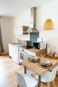 een keuken met een houten tafel en witte stoelen bij Appartement chaleureux proche gare in Saumur