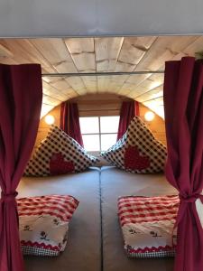 a bed in a tiny house with red curtains at Holz Fässla in Wolframs-Eschenbach