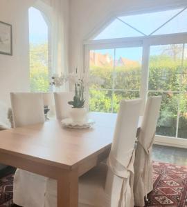a dining room table with white chairs and a large window at Villa De Panne in De Panne