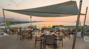 ein Restaurant mit Tischen und Stühlen auf einer Terrasse in der Unterkunft Crowne Plaza Muscat, an IHG Hotel in Muscat