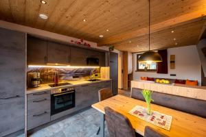 a kitchen with a wooden ceiling and a wooden table at Chalet Auszeit in Lermoos