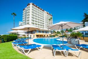 Una piscina con sillas y sombrillas y un edificio. en Hotel Monarque Torreblanca, en Fuengirola