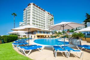 a pool with chairs and umbrellas and a building at Hotel Monarque Torreblanca in Fuengirola