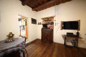 ein Wohnzimmer mit einem TV an der Wand und einem Tisch in der Unterkunft Alashkert Guesthouse ,Ալաշկերտ Հյուրատուն in Gjumri