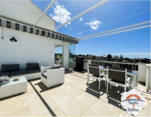 een patio met een bank en stoelen op een balkon bij Atico Las Palmeras Golf by Spain2home in Vélez-Málaga