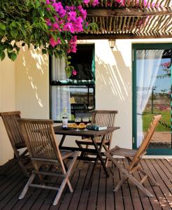 einen Tisch und Stühle auf einer Terrasse mit Blumen in der Unterkunft Tortoise Trail Lodge in Langebaan