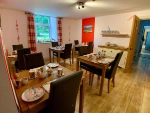 a dining room with tables and chairs and a room with red walls at Ewich House B&B in Crianlarich