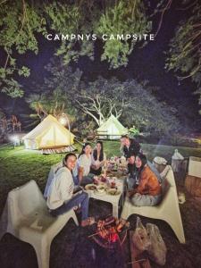 ムアクレクにあるCamp NYS Campsiteのテーブルの周りに座って食事をとる人々のグループ
