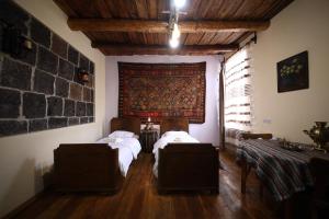 a bedroom with two beds and a stone wall at Alashkert Guesthouse ,Ալաշկերտ Հյուրատուն in Gyumri