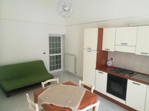 a small kitchen with a table and a green couch at Tra le cummerse in Locorotondo