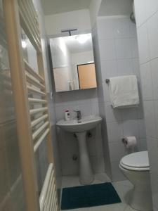 een badkamer met een wastafel, een toilet en een spiegel bij Tra le cummerse in Locorotondo