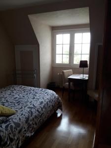 a bedroom with a bed and a table and a window at Chambre dans jolie demeure in Gouesnou
