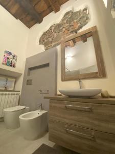 ein Badezimmer mit einem Waschbecken, einem WC und einem Spiegel in der Unterkunft Kindness art apartment in historic center in Arona