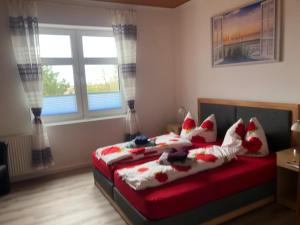 a bedroom with a bed with red and white pillows at Hotel & Restaurant Neptun in Norddorf