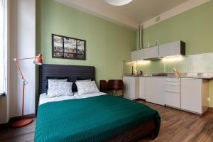 une chambre verte avec un lit et une cuisine dans l'établissement Golden Apartments Wroclaw&K24, à Wrocław