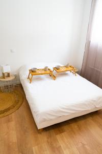Una cama blanca con dos mesas encima. en Spacieux appartement proche centre-ville, en Saumur