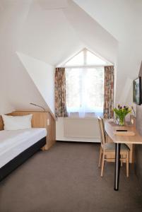 Schlafzimmer mit einem Bett, einem Tisch und einem Fenster in der Unterkunft Hotel Garni Meeresblick in Glowe