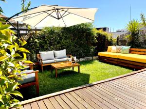 a garden with a couch and a table and an umbrella at Look At Me - Serviced Lofts & Studios in Porto