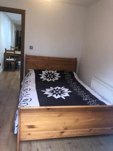 a bedroom with a wooden bed with a black and white blanket at Modern apartment in Bexley - 25 minutes from central London in Welling