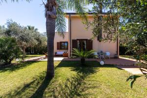 una casa con una palmera en el patio en Deliziosa Villa a 500 metri dal mare con Piscina, en Terrasini