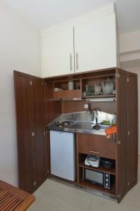 una pequeña cocina con armarios de madera y fregadero en Argalios Studios, en Kiónion