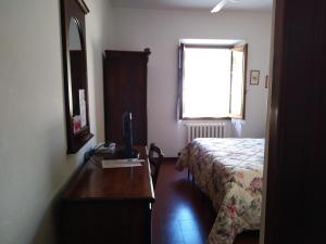 a bedroom with a bed and a desk with a television at Albergo Giovanni Da Verrazzano in Greve in Chianti