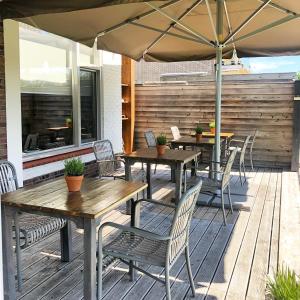 zwei Tische und Stühle mit Sonnenschirm auf einer Terrasse in der Unterkunft Hotel Panta Rhei Cadzand-Bad in Cadzand