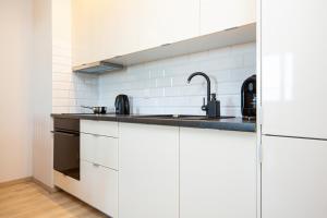 a kitchen with white cabinets and a sink at Apartamenty Bliska Praga by Renters in Warsaw