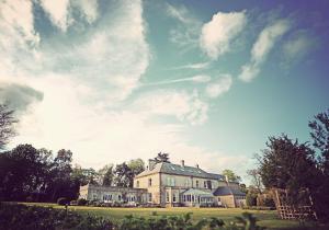 una casa grande en un campo con un cielo nublado en Broom Hall Country Hotel, en Saham Toney