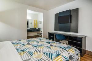 a bedroom with a bed and a desk with a television at Motel 6-Irving, TX - Dallas in Irving