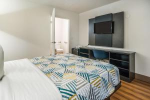 a bedroom with a bed and a desk with a television at Motel 6-Irving, TX - Dallas in Irving