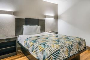 a bedroom with a bed with a colorful comforter at Motel 6-Irving, TX - Dallas in Irving