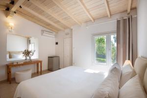 a white bedroom with a large bed and a window at Sanidiamonds in Sani Beach