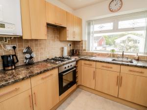 a kitchen with wooden cabinets and a clock on the window at Bryn Hafod in Conwy