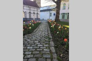 un chemin en pierre devant une maison fleurie dans l'établissement StudiO2 Ename, dakappartement in Vlaamse Ardennen, à Audenarde