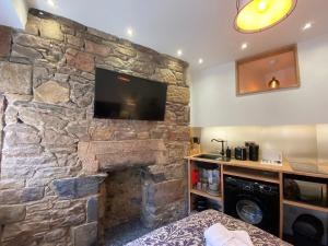 a room with a stone wall with a flat screen tv at Royal Mile Romance by Heritage Of Scotland LLP in Edinburgh