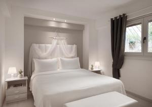 a white bedroom with a large white bed and a window at Sanidiamonds in Sani Beach