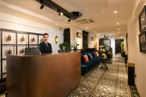 a man standing at a reception desk in a hotel lobby at Carillon Boutique Hotel in Hanoi
