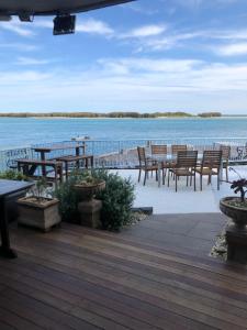 a deck with tables and chairs next to the water at Tripcony Quays in Caloundra