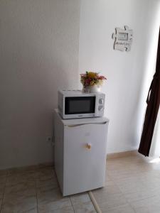 a microwave sitting on top of a white refrigerator at Garsoniera Saturn in Saturn +13 photos