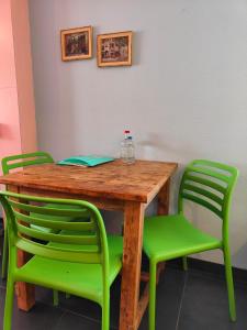 een houten tafel met groene stoelen en een fles erop bij Hotel Domburg4you in Domburg