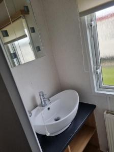 a bathroom with a sink and a mirror at 8 BERTH DELUXE CARAVAN Pg156 GOLDEN PALM CHAPEL ST LEONARDS in Chapel Saint Leonards