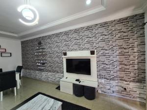 a living room with a tv and a brick wall at Asa Luxury 2Bedroom Apartment in Port Harcourt