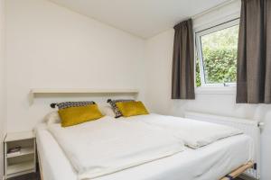 een wit bed in een kamer met een raam bij Valk 4 persons in Rijssen